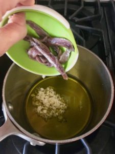 Olive oil, garlic and anchovies cooking in a saucepan