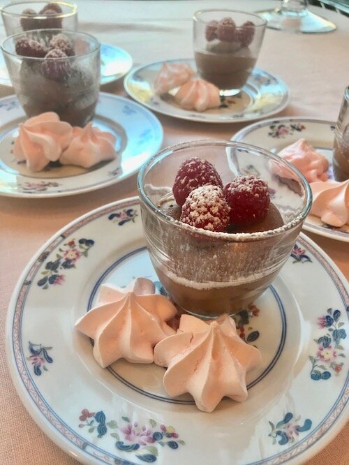 Chocolate Mousse topped with raspberries on a small plate with two pink meringues