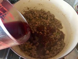 Red wine poured in to cooked mixture in a pot