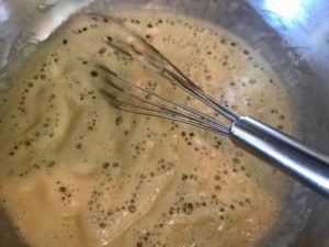 Melted butter and flour being stirred with a whisk in a pan