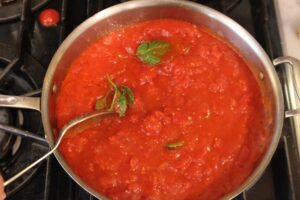 Chunky red tomato sauce in a pan garnished with basil