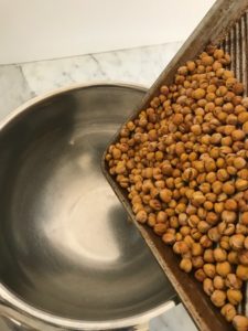 pouring chi-chi beans from oven hot tray to metal bowl