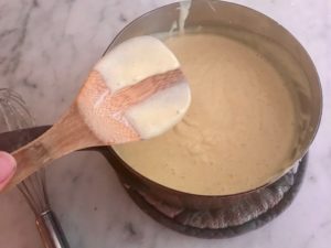 wooden spoon with custard mixture on it showing thickness