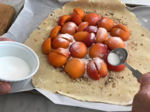 apricots on the dough with sugar being sprinkled over