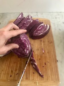 Red cabbage being cut on cutting board