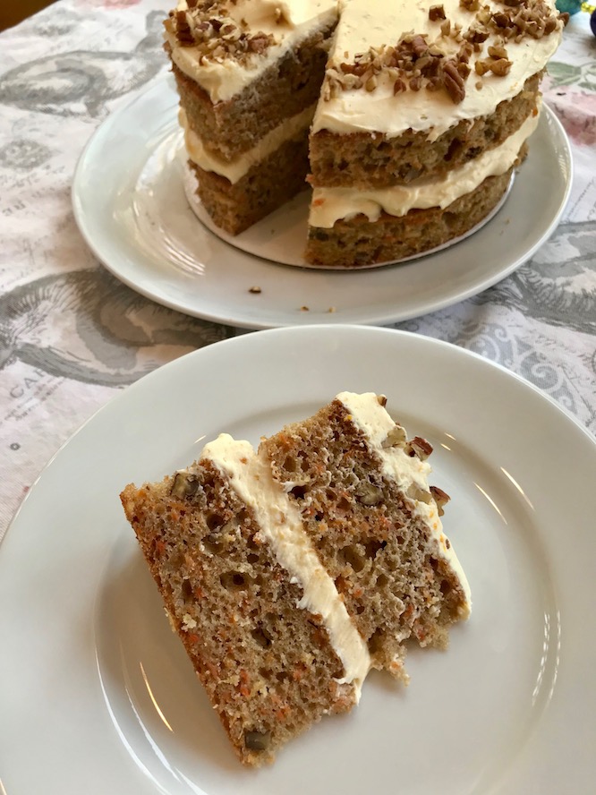 carrot cake with honey cream cheese icing on a serving plate