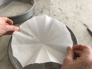round cake pan with parchment paper being placed in it