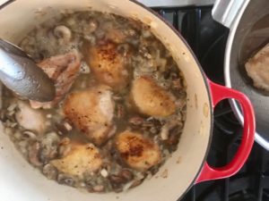 dutch oven with chicken thighs added back to the onion and mushroom mixture