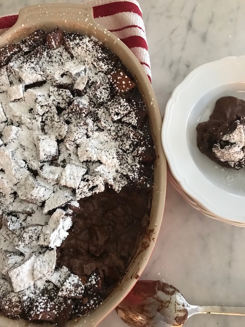 chocolate bread pudding in a baking dish and a slice on a serving plate