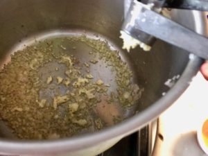adding garlic to a large pot