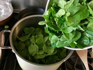 adding the spinach to the large pot