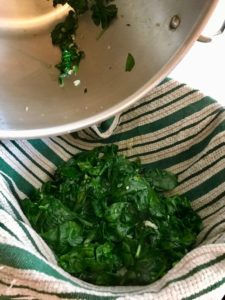adding the spinach to the towel lined colander