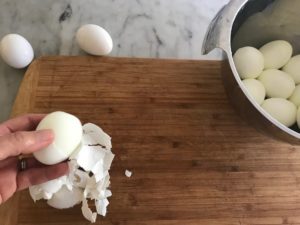 peeling hard boiled eggs on a cutting board