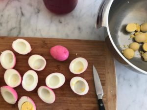 cutting the eggs in half on a cutting board and removing the yolks