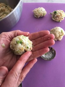two hands forming the crab cake mixture into balls