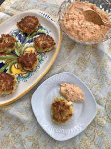 crab cake with remoulade sauce on a small plate with the serving dish next to it