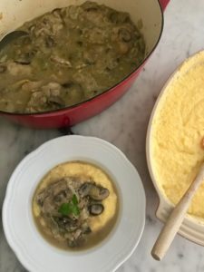 polenta being served under the chicken with mushrooms and artichokes