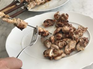 removing the chicken from the skewers onto a plate