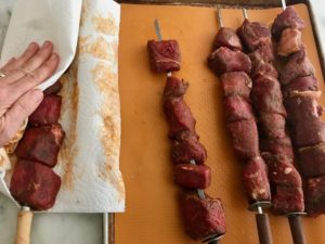 sirloin on skewers being patted dry with a paper towel