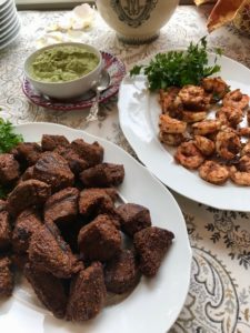 beef and shrimp kabobs on a serving plate with side of avocado tzatziki