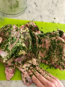 herb mixture being rubbed all over the leg of lamb