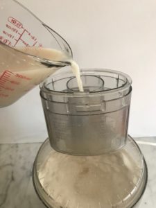 adding the water and yeast mixture to the food processor