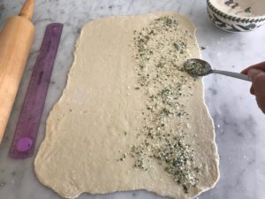 rolled out dough with the herb mixture being added to one side