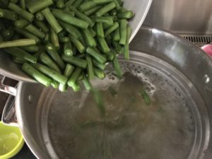 adding the green beans to the pasta and boiling water