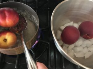 pot with boiling water with peaches in it, bowl with ice water and peaches