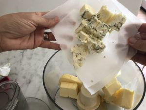 bleu cheese being added to the food processor with the butter