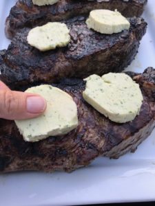 putting butter on the on cooked steaks
