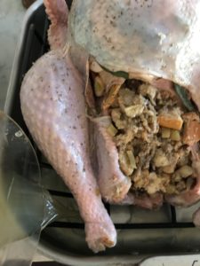 turkey in a roasting pan and rack with stock being added