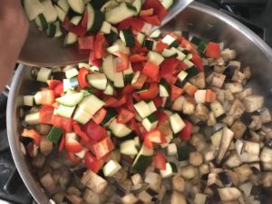 adding peppers and zucchini to the eggplant mixture