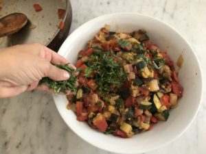 ratatouille in a serving bowl with being garnished with basil