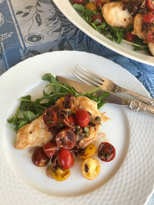 chicken over arugula with tomato mixture on top