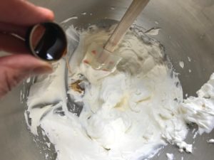 vanilla extract being added to the whipped cream