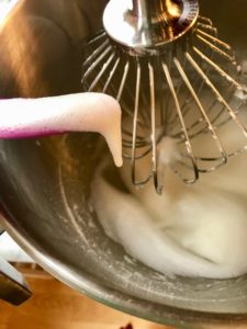 whisking bowl with egg whites being poured in