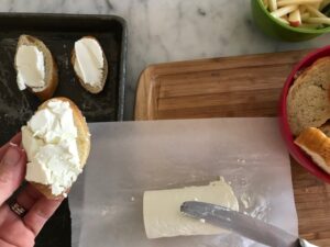 spreading goat cheese onto the baguette slices
