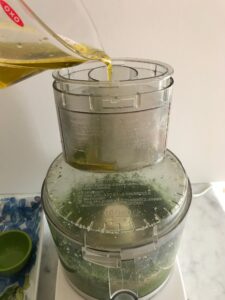 olive oil being added to the food processor