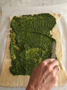 spreading pesto on the pastry