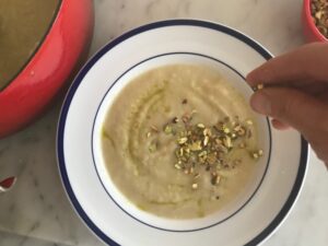 sprinkling chopped pistachios on top of the soup