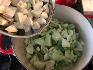adding the chopped celery root and fennel to the pot