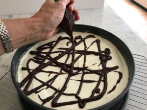 drizzling the ganache on the cheesecake