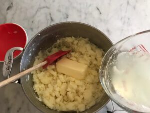 mashing the potatoes with butter and cooking water