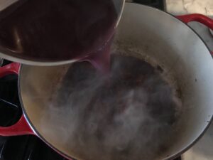adding the wine to the dutch oven