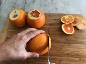 cutting off the tops and bottoms of the oranges