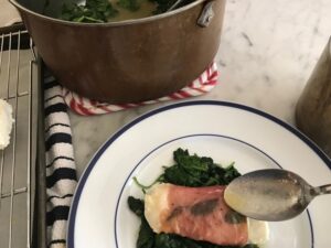 drizzling sauce on the fish and spinach