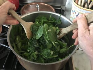 spinach being tossed with the garlic and oil