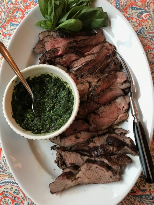 grilled leg of lamb on a serving plate with sauce