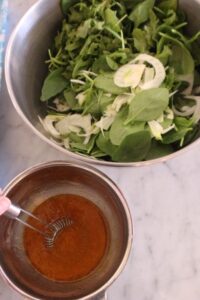 whisking together the dressing for the greens